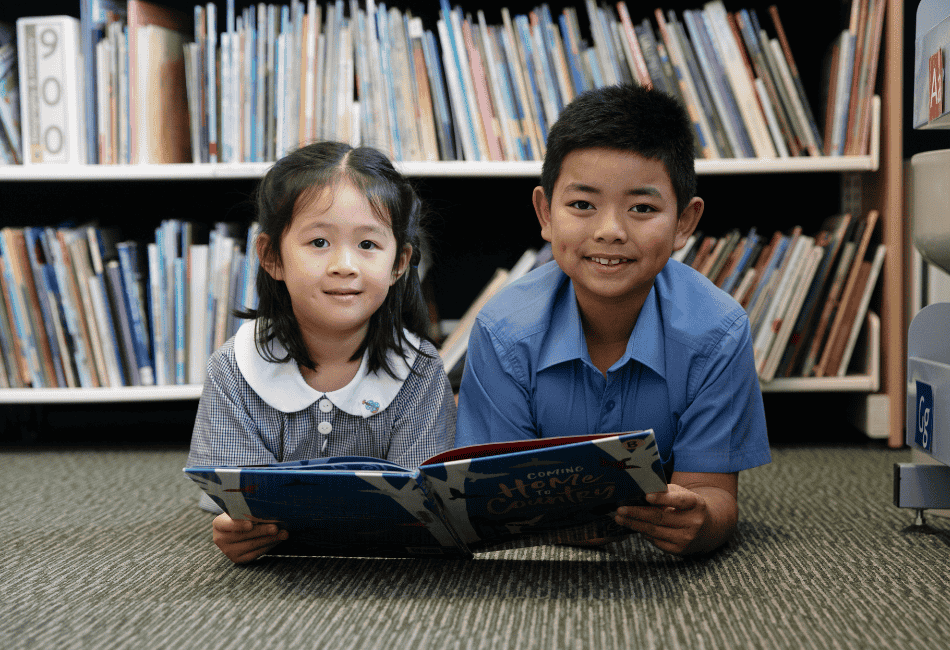 A photo of two St Martha's Catholic Primary School Strathfield's students smiling in the library, and on the journey to 2025 NAPLAN results success